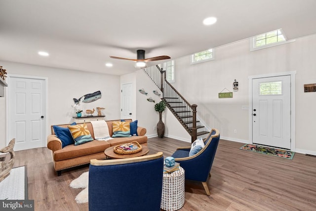 living area with stairs, ceiling fan, and wood finished floors