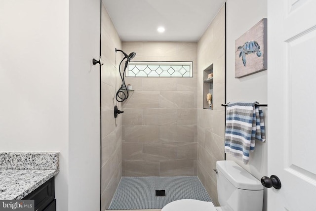 full bath featuring vanity, a tile shower, and toilet