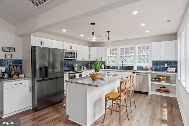 kitchen featuring backsplash, white cabinetry, appliances with stainless steel finishes, and wood finished floors
