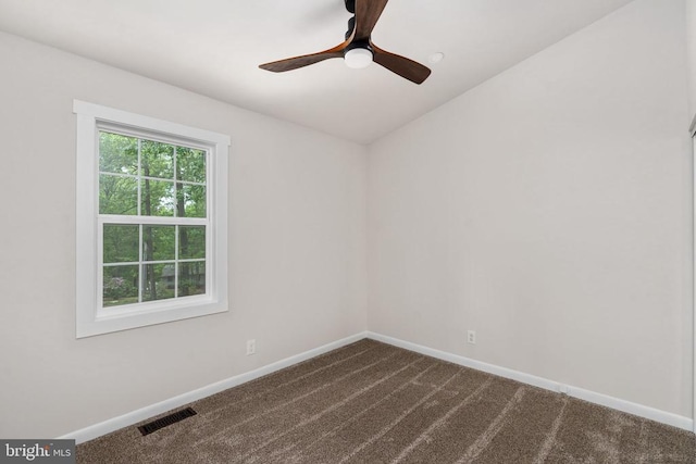 unfurnished room featuring baseboards, visible vents, ceiling fan, and dark colored carpet
