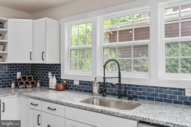 kitchen with white cabinets, backsplash, open shelves, and a sink