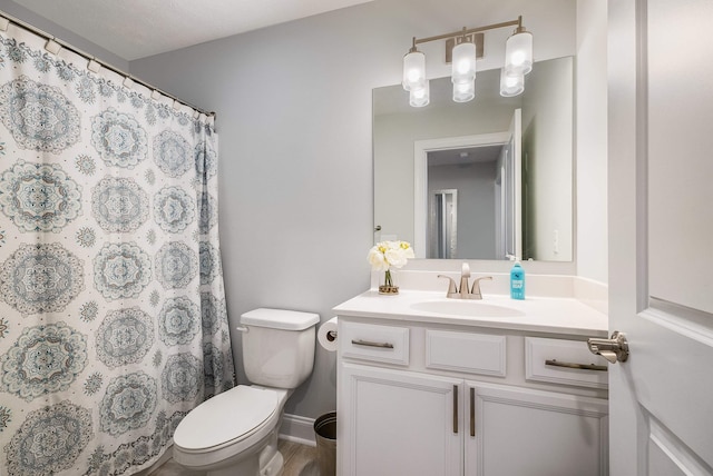bathroom featuring a shower with curtain, vanity, toilet, baseboards, and wood finished floors