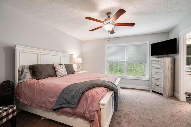 bedroom with a textured ceiling, a ceiling fan, light carpet, and visible vents