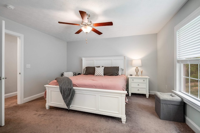 carpeted bedroom featuring baseboards, ceiling fan, and multiple windows