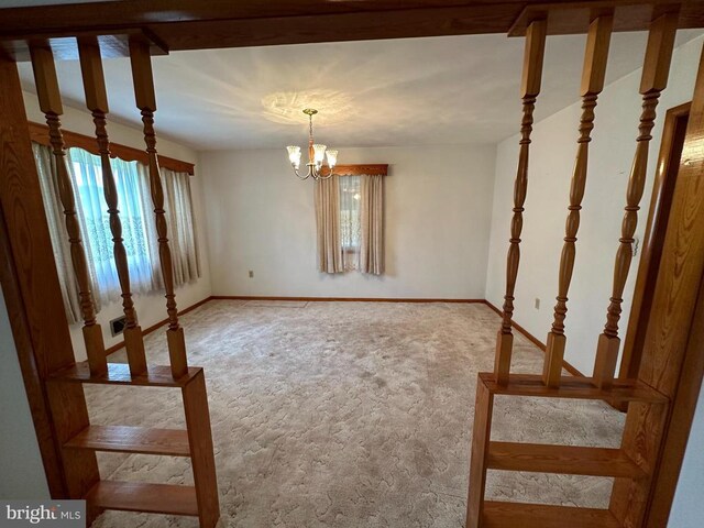 carpeted empty room with a chandelier