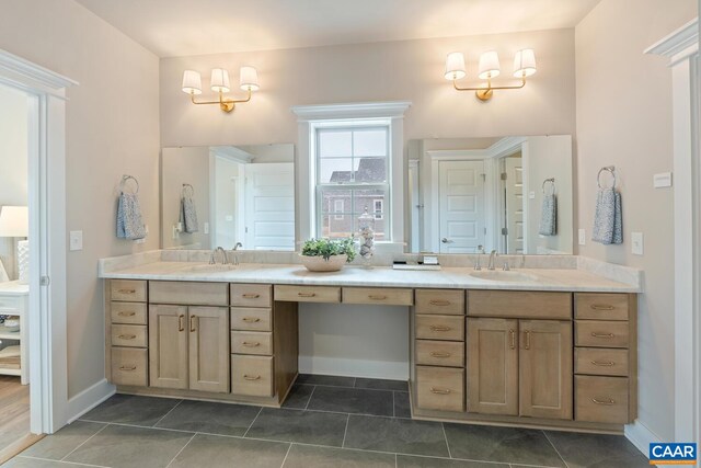 bathroom with baseboards, double vanity, a sink, and tile patterned floors