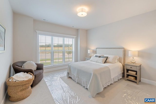 bedroom featuring baseboards, visible vents, and light colored carpet