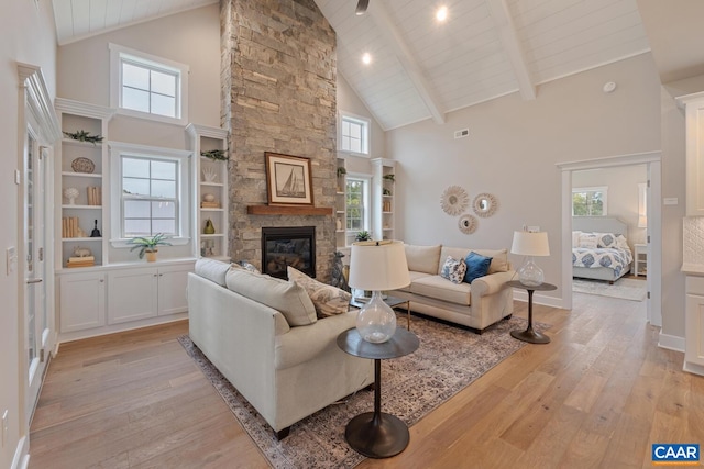 living area with high vaulted ceiling, beam ceiling, a fireplace, and light wood-style flooring