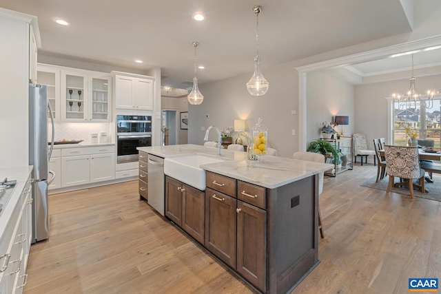 kitchen featuring light wood-type flooring, appliances with stainless steel finishes, white cabinets, and a sink