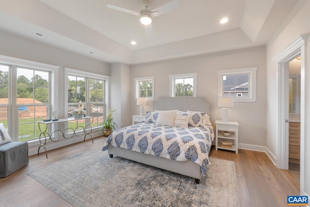 bedroom with baseboards, visible vents, a raised ceiling, wood finished floors, and recessed lighting