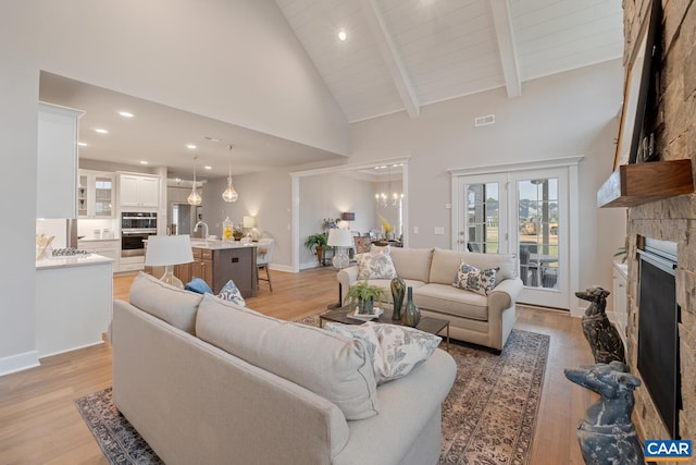 living room with high vaulted ceiling, a fireplace, visible vents, and light wood-style floors