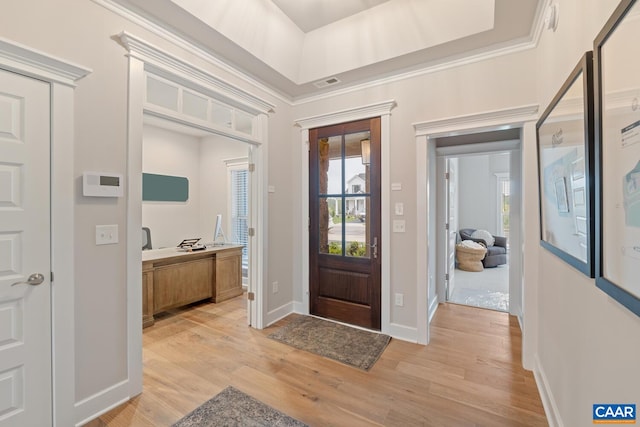 foyer entrance featuring a tray ceiling, crown molding, visible vents, light wood-style flooring, and baseboards