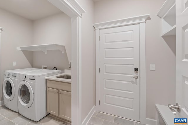 clothes washing area featuring cabinet space, light tile patterned flooring, a sink, washer and dryer, and baseboards