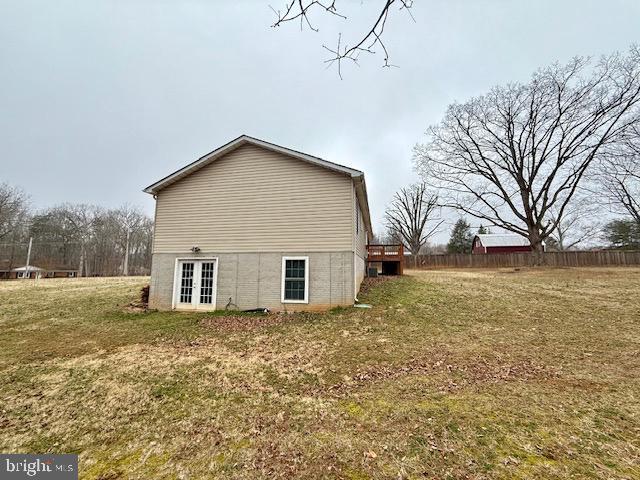 view of property exterior featuring french doors, a yard, and fence