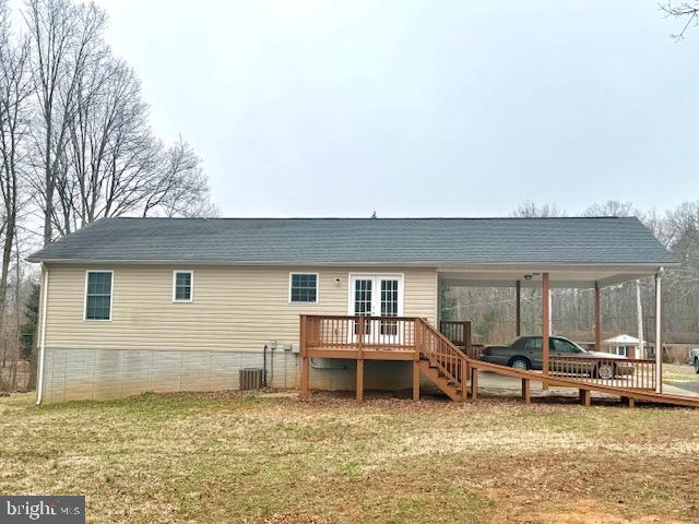 back of property with a wooden deck, an attached carport, central AC unit, and a lawn