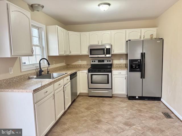 kitchen featuring white cabinets, stainless steel appliances, and a sink