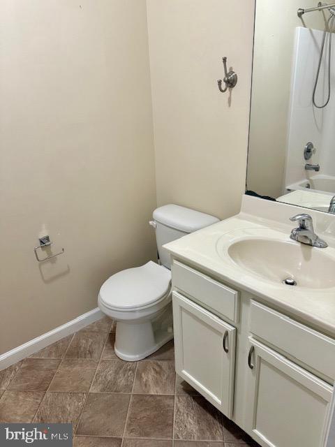 bathroom with toilet, vanity, shower / bathing tub combination, and baseboards