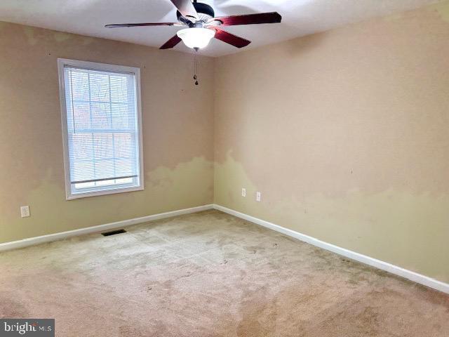 spare room featuring visible vents, ceiling fan, and carpet floors