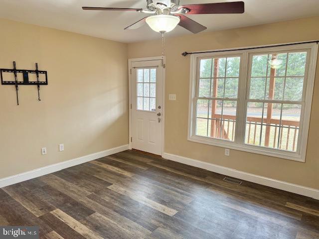 interior space with dark wood finished floors, visible vents, baseboards, and ceiling fan