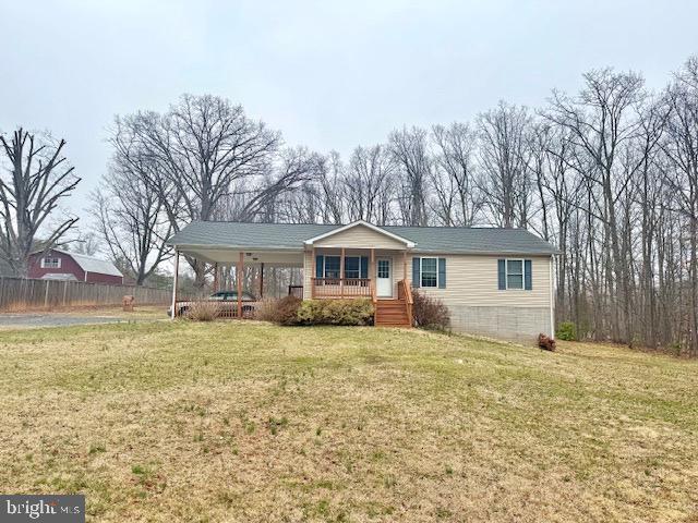 view of front of property featuring a carport, a porch, a front lawn, and fence