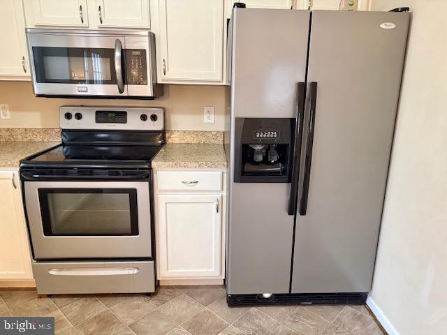 kitchen with stainless steel appliances, white cabinetry, and light countertops