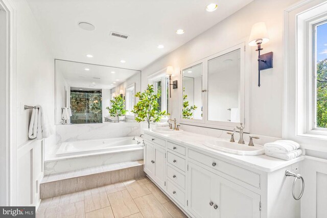 bathroom with a relaxing tiled tub and vanity