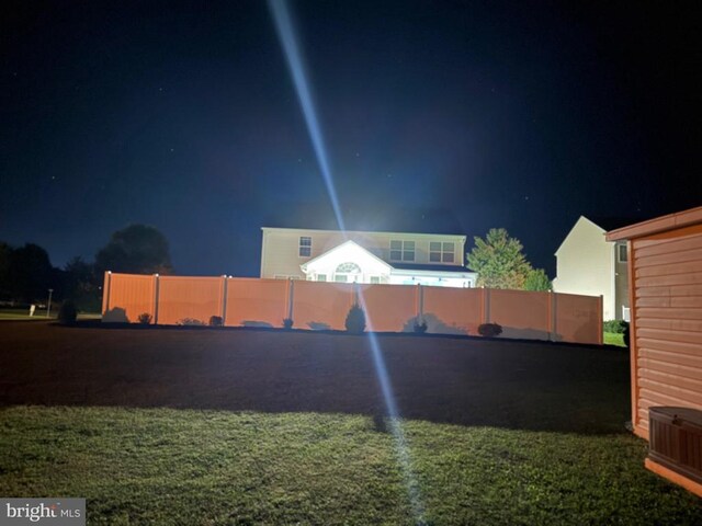 yard at night featuring central air condition unit