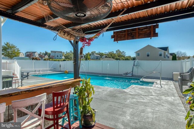 view of pool featuring pool water feature, exterior bar, and a patio