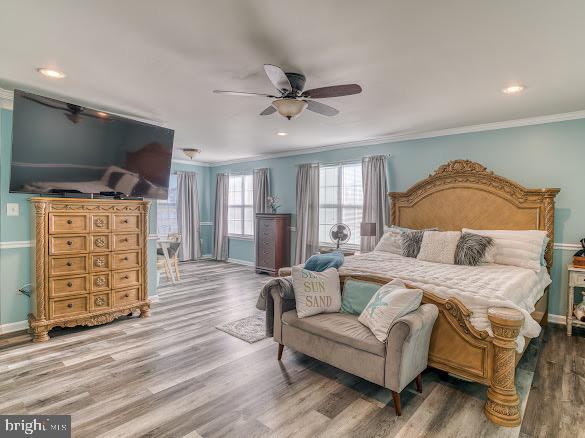 bedroom with ceiling fan, ornamental molding, and wood-type flooring