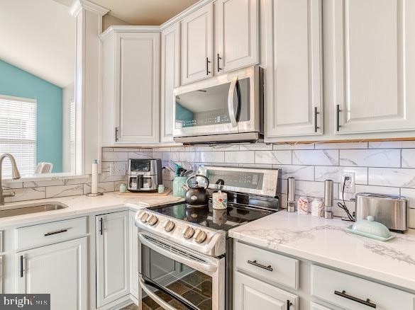 kitchen featuring tasteful backsplash, appliances with stainless steel finishes, sink, and white cabinets