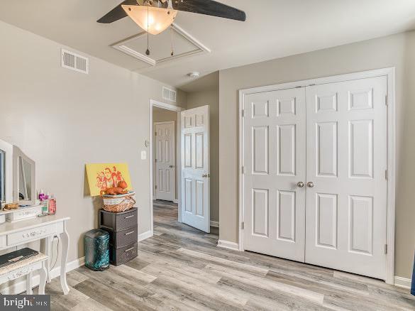 bedroom with ceiling fan, light wood-type flooring, and a closet