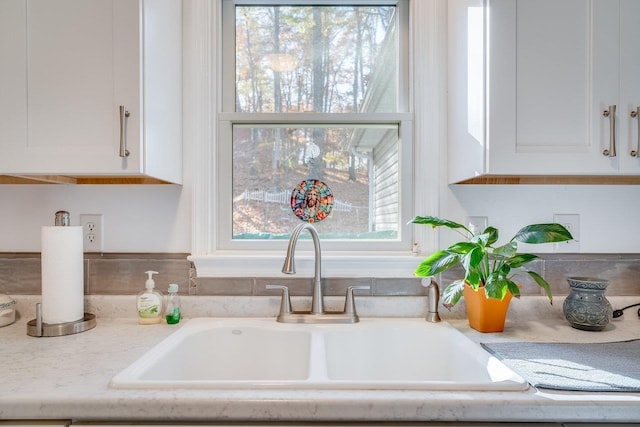 details with sink, white cabinets, and light stone counters