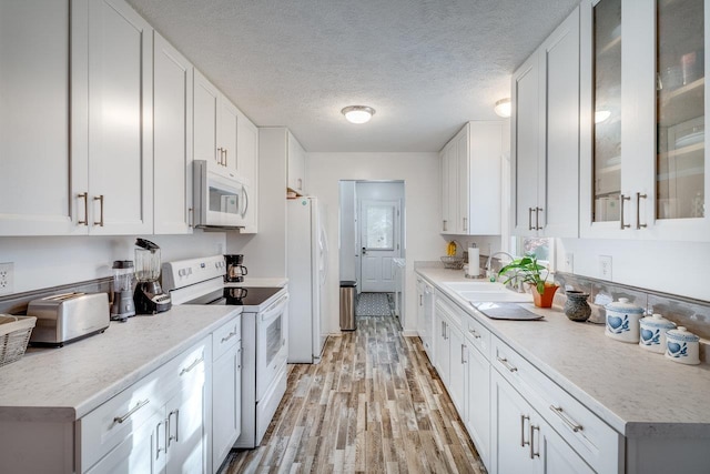 kitchen with sink, white appliances, white cabinetry, light hardwood / wood-style floors, and a textured ceiling