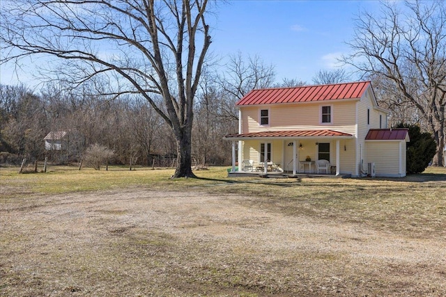 view of front of house with a front yard, covered porch, metal roof, and a standing seam roof