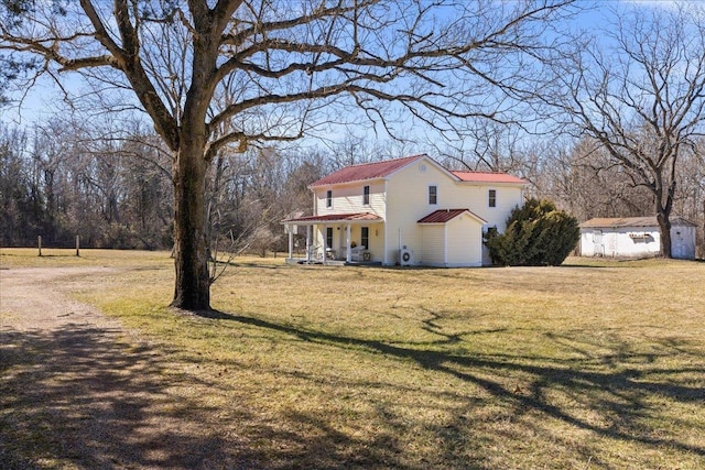 view of front of house with covered porch, a shed, an outbuilding, and a front yard