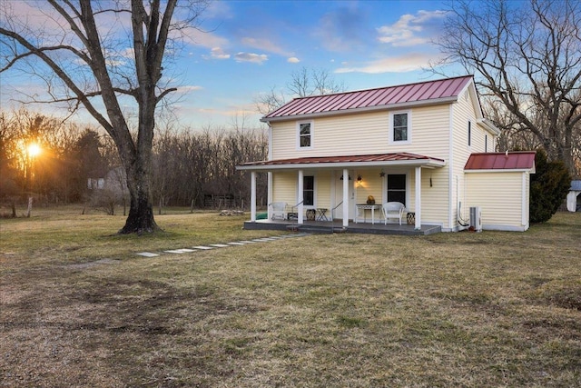 view of front facade featuring a porch, a standing seam roof, a yard, and metal roof