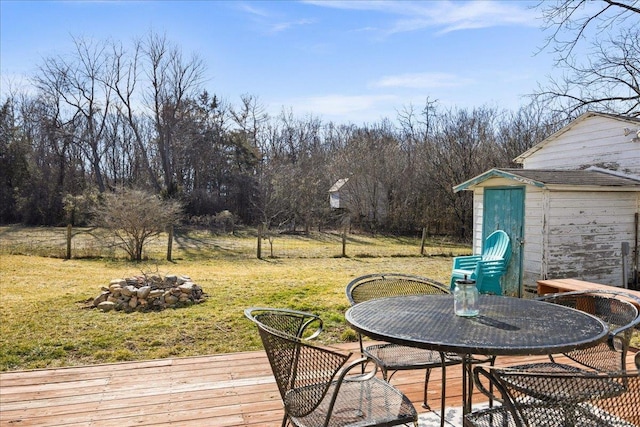 deck with a storage shed, an outdoor fire pit, a lawn, and an outbuilding