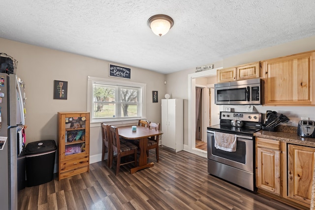 kitchen featuring dark wood-style flooring, appliances with stainless steel finishes, light brown cabinets, a textured ceiling, and baseboards