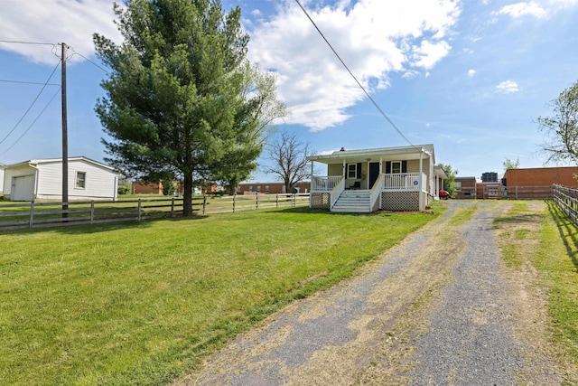 view of yard featuring covered porch, fence, and driveway