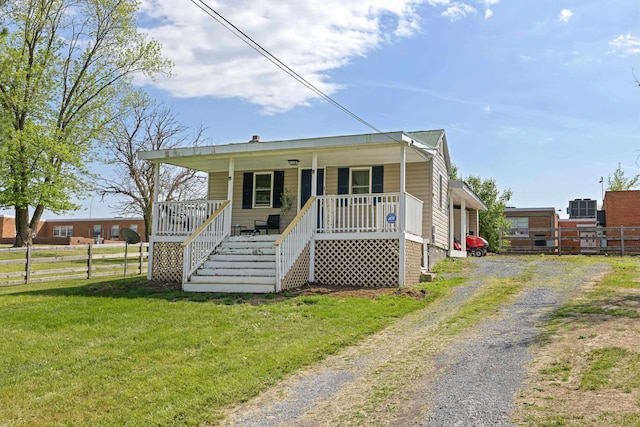 bungalow with a porch, driveway, stairway, fence, and a front lawn