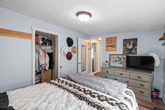 bedroom with a textured ceiling, wood finished floors, and a closet
