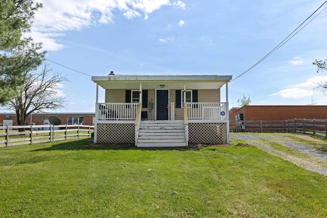 view of front facade featuring fence, covered porch, and a front yard