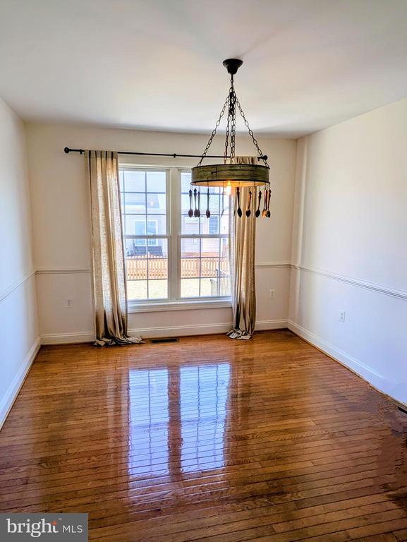 unfurnished dining area featuring wood finished floors, visible vents, and baseboards