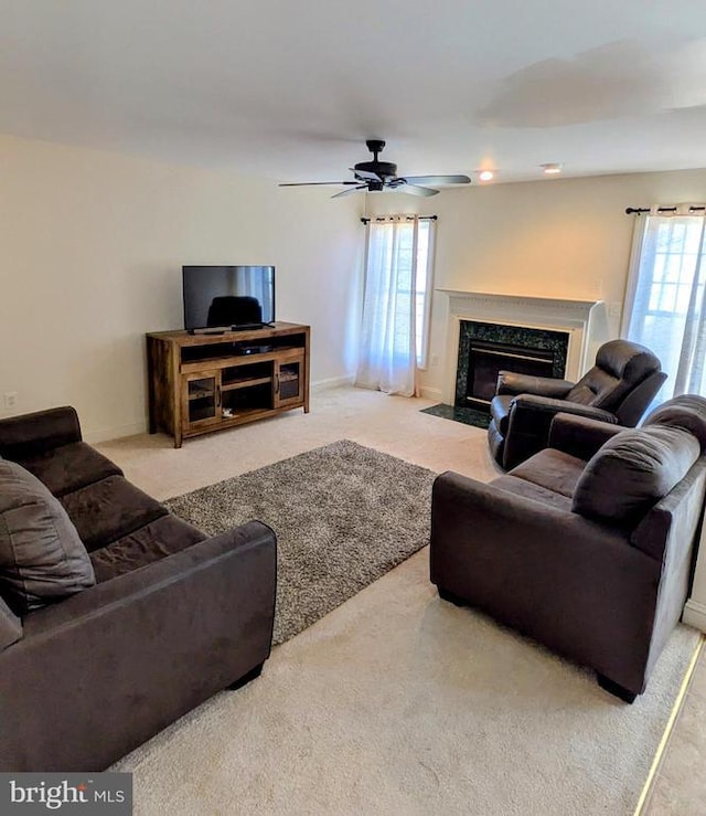 living room featuring a ceiling fan, light colored carpet, a wealth of natural light, and a high end fireplace