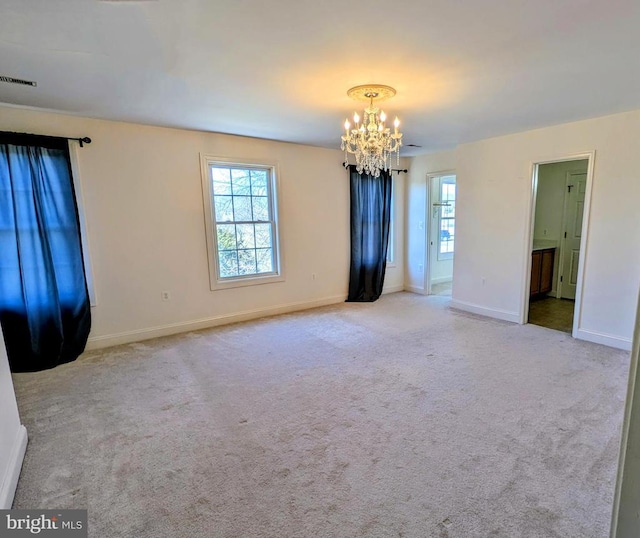 empty room with light carpet, baseboards, visible vents, and a chandelier