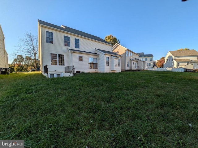 rear view of house with a lawn and fence