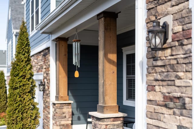 view of exterior entry featuring stone siding and a porch