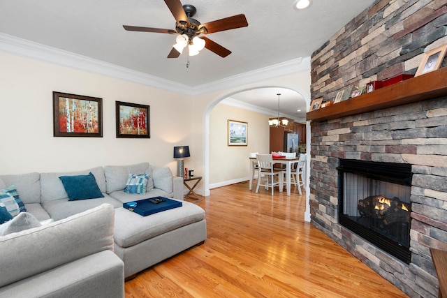 living area with crown molding, baseboards, light wood-type flooring, ceiling fan with notable chandelier, and arched walkways