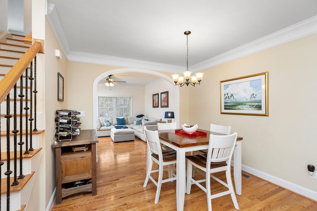 dining area featuring stairway, baseboards, arched walkways, light wood-style floors, and crown molding