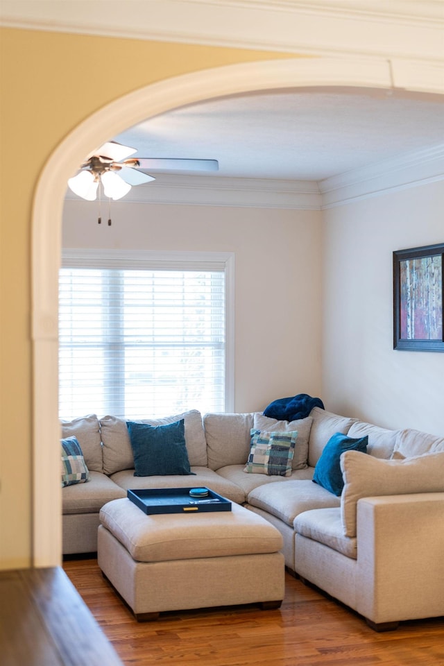 living room featuring crown molding, wood finished floors, arched walkways, and ceiling fan